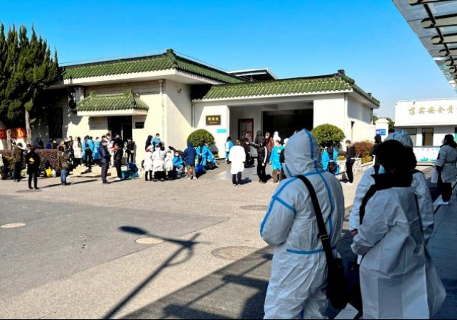  People wearing PPE wait outside a funeral home in Shanghai. Photograph: Staff/Reuters