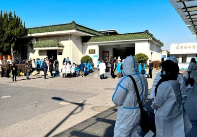  People wearing PPE wait outside a funeral home in Shanghai. Photograph: Staff/Reuters